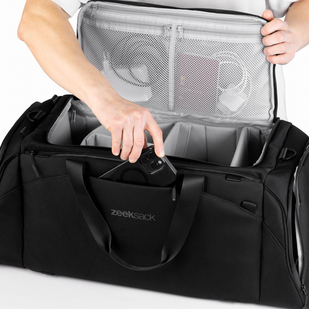 The Duffelbag med en hånd som legger ned en mobiltelefon i den ytre frontlommen.