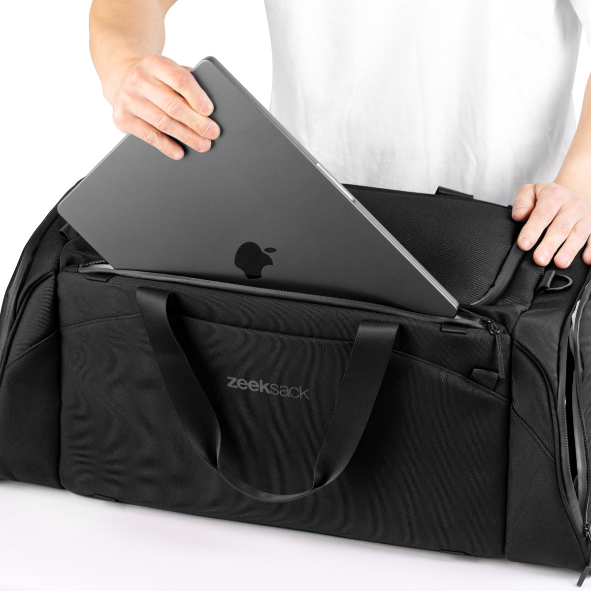 Person legger en MacBook ned i det polstrede laptoprommet i The Duffelbag.