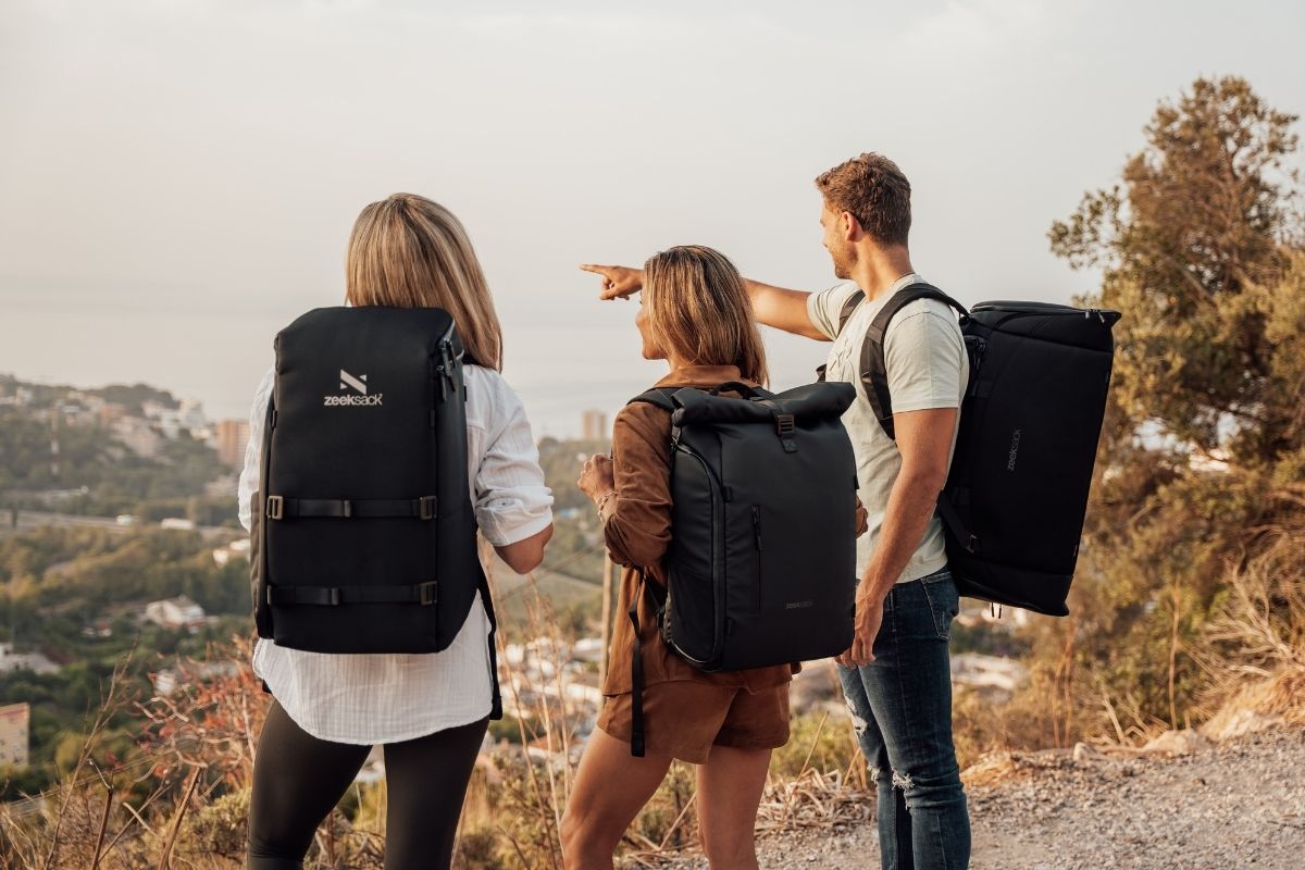 Tre personer med Zeeksack-ryggsekker nyter utsikten på tur i fjellet.
