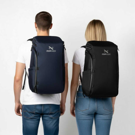 Mann og kvinne i hvite t-skjorter og jeans står vendt bort fra kameraet med svarte ryggsekker.