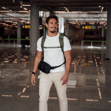 Zeeksack - Mann med The Underseat 15L på ryggen og Crossbody Organizer rundt livet på en flyplass.