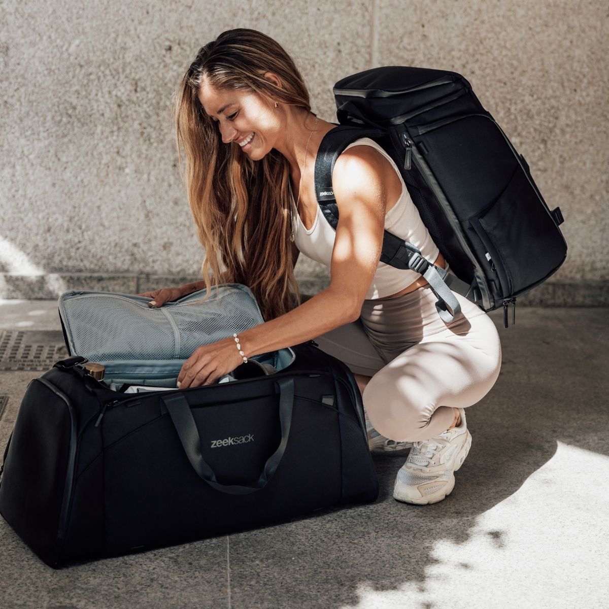 Kvinne pakker med seg Zeeksack-duffelbag og ryggsekk – perfekt til trening, reise og hverdagsbruk.