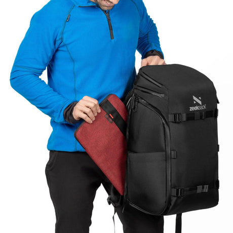 Person legger ned en laptopmappe i sidelommen på Zeeksack Organizer.